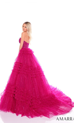 A woman wears the Long Formal Dress 88099 by Amarra, featuring a strapless sheer corset bodice, bright pink ruffled layered skirt, and a dramatic long train, standing against a white background.