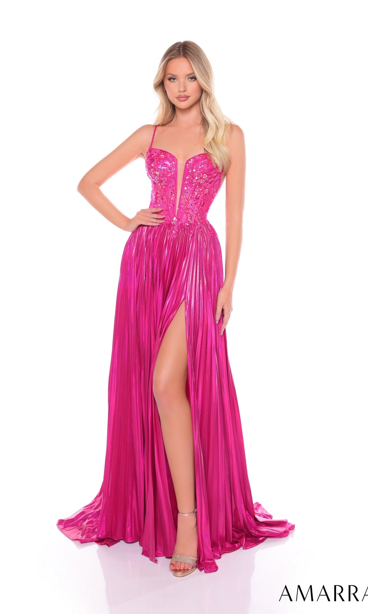 A woman wearing the Long Formal Dress 88113 by Amarra—a bright pink, floor-length pleated A-line dress featuring a thigh-high slit, sequin-embellished bodice, and spaghetti straps—stands against a white background.