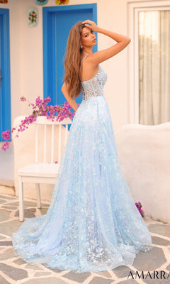 A woman stands outdoors on a stone patio with her back to the camera, wearing the Long Formal Dress 88126 by Amarra, a light blue lace-embellished A-line gown, near a white chair and blue doors.