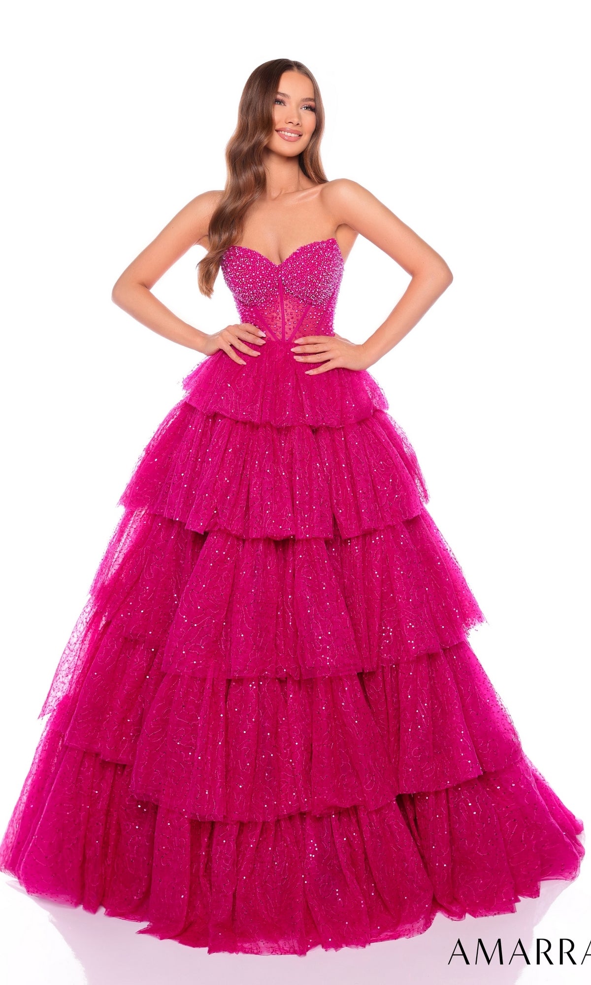 A woman poses with hands on hips in the Long Formal Dress 88131 by Amarra, a strapless, tiered hot pink glitter tulle gown adorned with sequins, set against a white background.