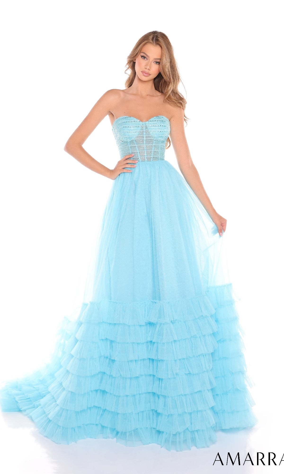 A woman poses against a plain white background in the Amarra 88277 strapless prom ball gown featuring a tulle fabric, sweetheart neckline, and an A-line ruffled skirt.