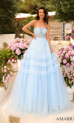 A woman wearing the Amarra Strapless Sheer-Bodice Prom Ball Gown 88794 with a glitter-tulle overlay stands outside near pink flowers and greenery, smiling at the camera.