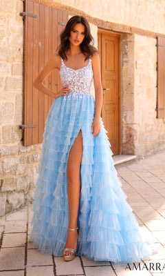 A woman stands outside in the Amarra Deep V-Back Long Ruffled Prom Dress 88833—a sleeveless, light blue tulle gown with a lace bodice and thigh-high slit. A stone wall and wooden door complete the elegant scene.