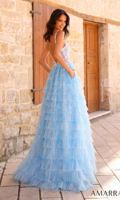 A woman in the Amarra Deep V-Back Long Ruffled Prom Dress 88833 stands outdoors by a stone wall and wooden door, looking over her shoulder.