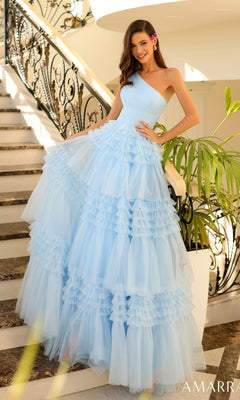 A woman stands on a staircase framed by greenery and an ornate railing, wearing the Amarra One-Shoulder Long Ruffled Prom Gown 88863 in light blue, featuring tiered tulle and holding part of the skirt.