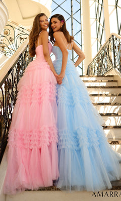 Two women stand side by side on a staircase, each wearing the Amarra One-Shoulder Long Ruffled Prom Gown 88863—one in pink, one in blue—holding hands and smiling at the camera.