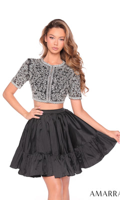 A woman poses in the Amarra 88902 short two-piece party dress, featuring a silver embellished short-sleeve bodice and a high-waisted black ruffled skirt against a white background.