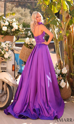 A woman wearing the Amarra 88914 long prom dress poses outdoors near white flower arrangements, a scooter, and lush green plants.
