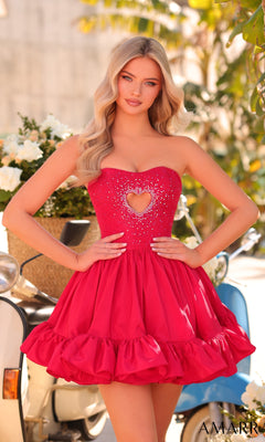 A woman poses outdoors in front of flowers and a scooter, wearing the Amarra 88933 Ruffled Strapless Short Hoco Dress with a heart cutout and rhinestone embellishments, hands on hips.