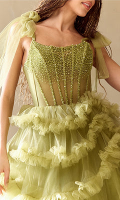 A woman wears the Amelia Couture 8900, a Ruffled Long Prom Ball Gown with an embellished sheer corset, beaded bodice, tulle ruffles, and ribbon shoulder straps.
