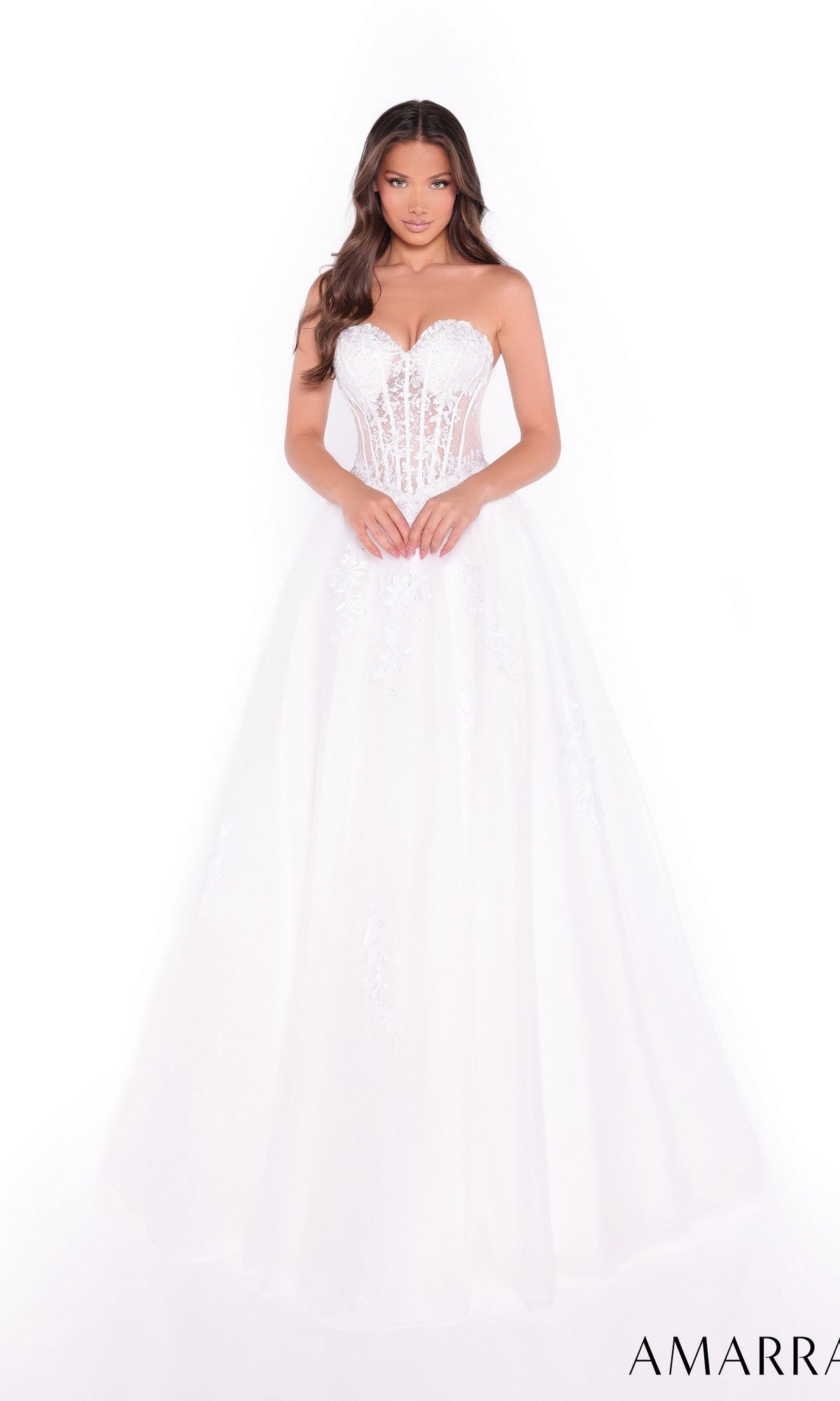 A woman in the Amarra 89011 Lace-Up Strapless Prom Ball Gown, featuring a sheer boned bodice and floral embellishments, stands elegantly against a white background.