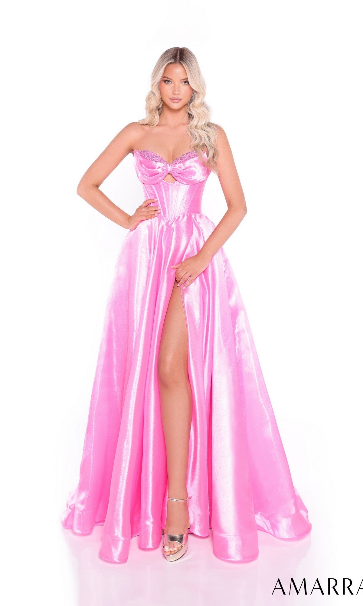 A woman poses against a white background wearing the Amarra 89072 long prom dress, which features a shiny, strapless design with a sweetheart neckline, corset bodice, and high-leg front slit.