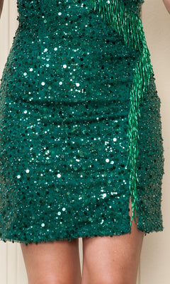 Close-up of a person wearing the Sequin Fringe Short Homecoming Dress 8926, a green strappy-back party dress with sequins, a thigh-high slit, and sparkling green beaded fringe detail.