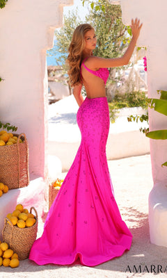 A woman wearing the Amarra 89323 long pink prom dress stands outside by white walls and baskets of lemons, glancing over her shoulder.