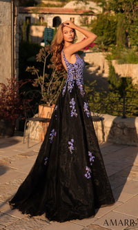 A woman poses outdoors in the Amarra 89373 long prom dress, featuring a sleeveless design, purple floral accents, and a fitted silhouette, as she stands on a stone patio surrounded by lush greenery.