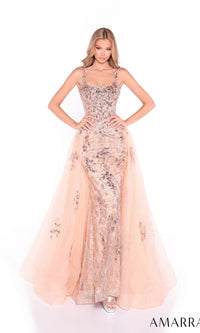 A woman stands hands on hips against a white background, wearing the Amarra 89373 long prom dress—a sleeveless, fitted gown with intricate silver details and a floral-embellished tulle overskirt.