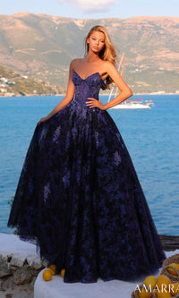 A woman wearing the Amarra 89415 long prom dress, featuring a strapless bodice and an a-line tulle skirt, stands outdoors by the water with mountains and a sailboat in the background.
