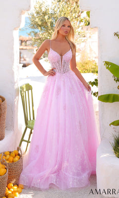 A woman stands outdoors, surrounded by baskets of lemons and white stone walls, wearing the Amarra 89425 long prom dress—a pale pink, floor-length gown with thin straps and a sheer corset bodice.