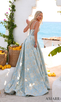 A woman in the Amarra 89437 long prom dress stands outdoors by baskets of lemons, glancing over her shoulder with the sea behind her.