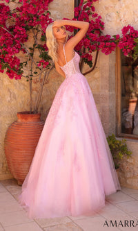 Wearing the Amarra 89509 long prom dress—a light pink gown with a lace corset bodice and tulle A-line skirt—a woman stands outdoors beside a stone wall and large vase, with pink flowers in the background.