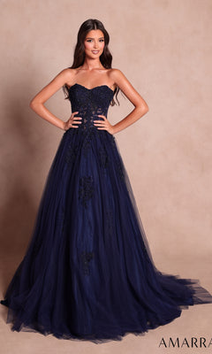 A woman wearing the Amarra 89627 long prom dress in navy, featuring a strapless design and beaded floral lace detailing, stands in front of a beige background.