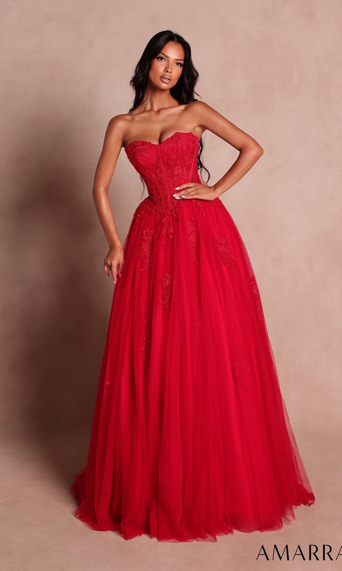 Wearing the Amarra 89627 long prom dress in red—with its strapless, floor-length silhouette, fitted bodice, and beaded floral lace details—a woman stands against a beige background.