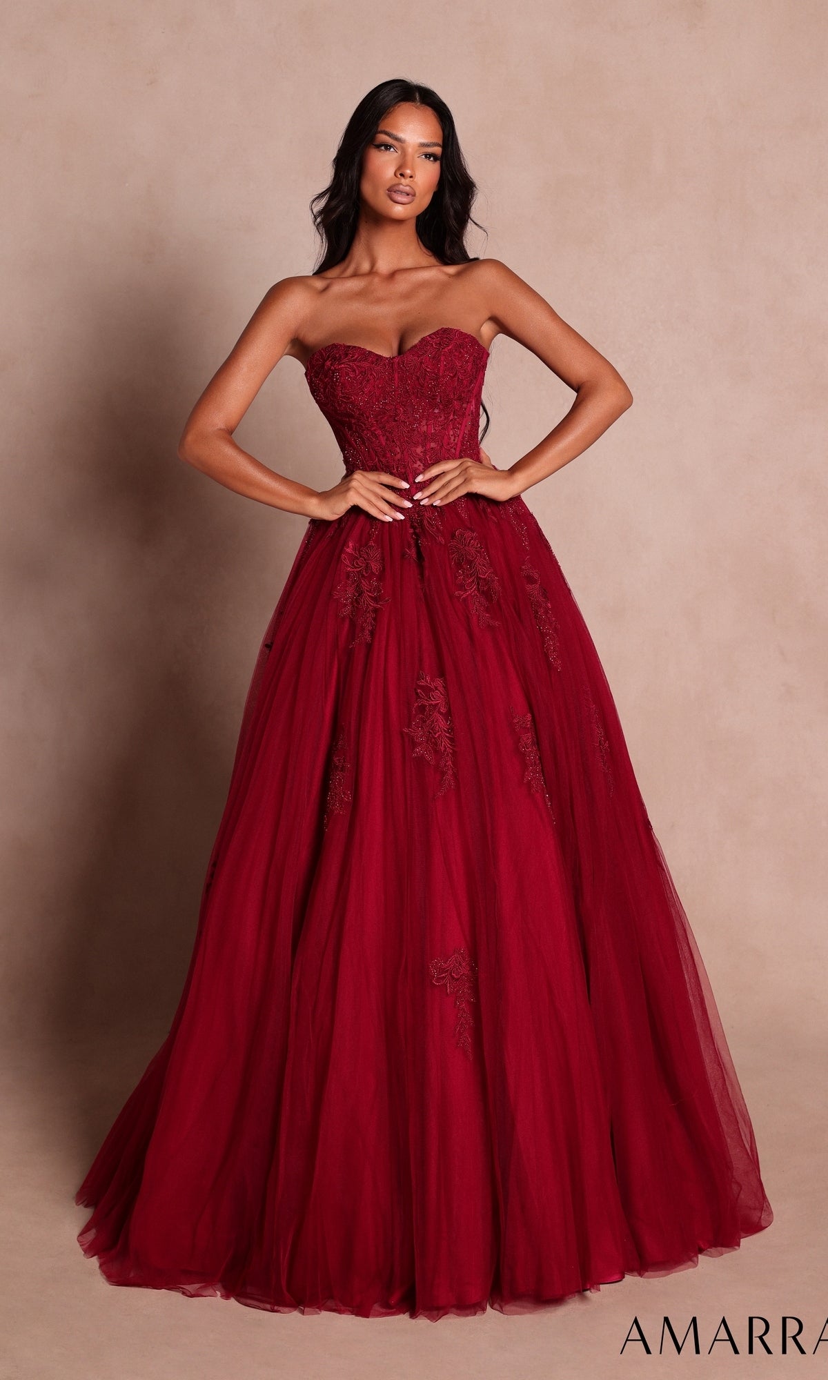 A woman wearing the Amarra 89627 Long Prom Dress in wine—a strapless, floor-length gown featuring beaded floral lace detailing—stands against a neutral background.