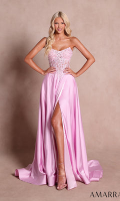 A woman stands with her hands on her hips against a plain beige background, wearing the Amarra 89628 long prom dress in light pink, featuring a strapless sweetheart neckline, a beaded corset bodice, and a high slit.