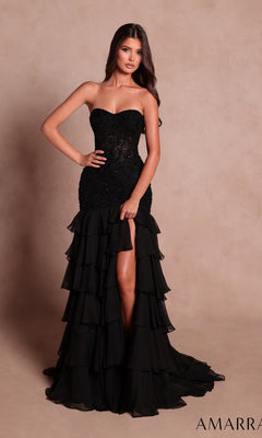 A woman wearing the Amarra 89631 long prom dress in black, featuring a strapless fitted bodice, tiered ruffles along the layered skirt, and a front slit, stands against a plain beige background.