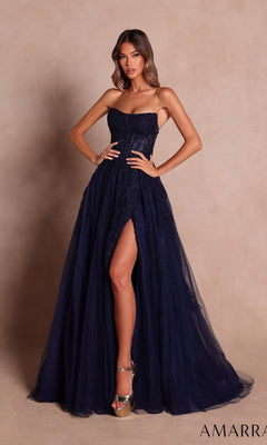 A woman wearing the Amarra 89684 long prom dress in navy, featuring a strapless neckline and a thigh-high slit, paired with metallic high heels, poses against a beige backdrop.