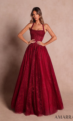 A woman wearing the Amarra 89685 Prom Ball Gown in wine—a floor-length, fitted lace gown with a halter neckline and delicate glitter floral print—is standing against a beige background.