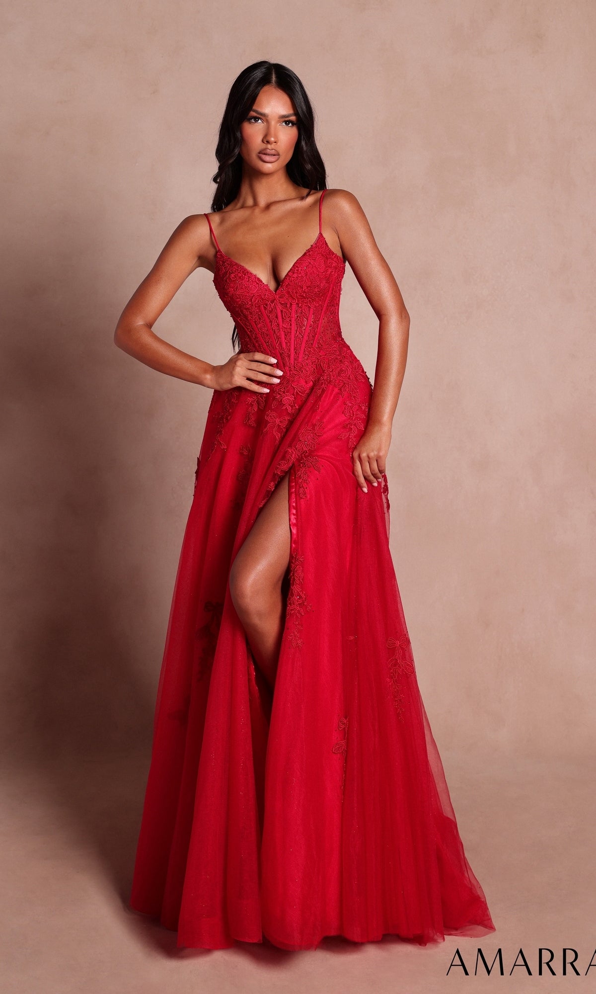 A woman stands against a beige background wearing the Amarra 89693 long red prom dress, featuring a sleeveless design, boned-corset bodice, floor-length silhouette, and a thigh-high slit.