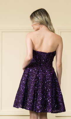 A woman with her hair down stands facing away in front of a cream wall, wearing the Strapless Sequin A-Line Homecoming Dress 8974—a knee-length purple dress shimmering with sequins.