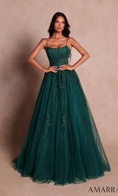 A woman wearing the Amarra 89806 long prom dress in emerald—an elegant, sleeveless, floor-length gown with floral lace details—stands against a plain beige background.