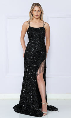 A woman wears the Strappy-Back Fringed Long Sequin Prom Dress 8982, featuring thin straps, a high slit, and fringe details for an elegant look paired with strappy heels.