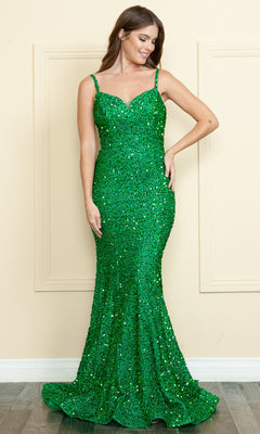 A woman wearing the Lace-Up-Back Long Sequin Prom Dress 9002, a fitted, floor-length green gown with thin straps and shimmering sequins, stands against a neutral wall on a wooden floor.