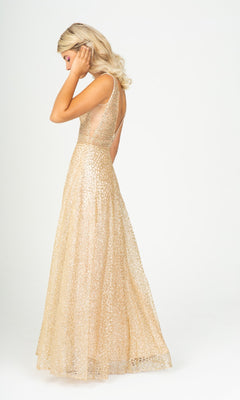 A woman in the Sleeveless Long Glitter Formal Dress: Eureka 9005, a floor-length gold patterned gown, stands against a plain white background, facing slightly away and touching her hair.