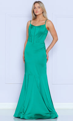 A woman poses against a light wall in the Stretch-Charmeuse Long Mermaid Prom Dress 9006, an emerald-colored, sleeveless gown with thin straps and a fitted, flared floor-length skirt.