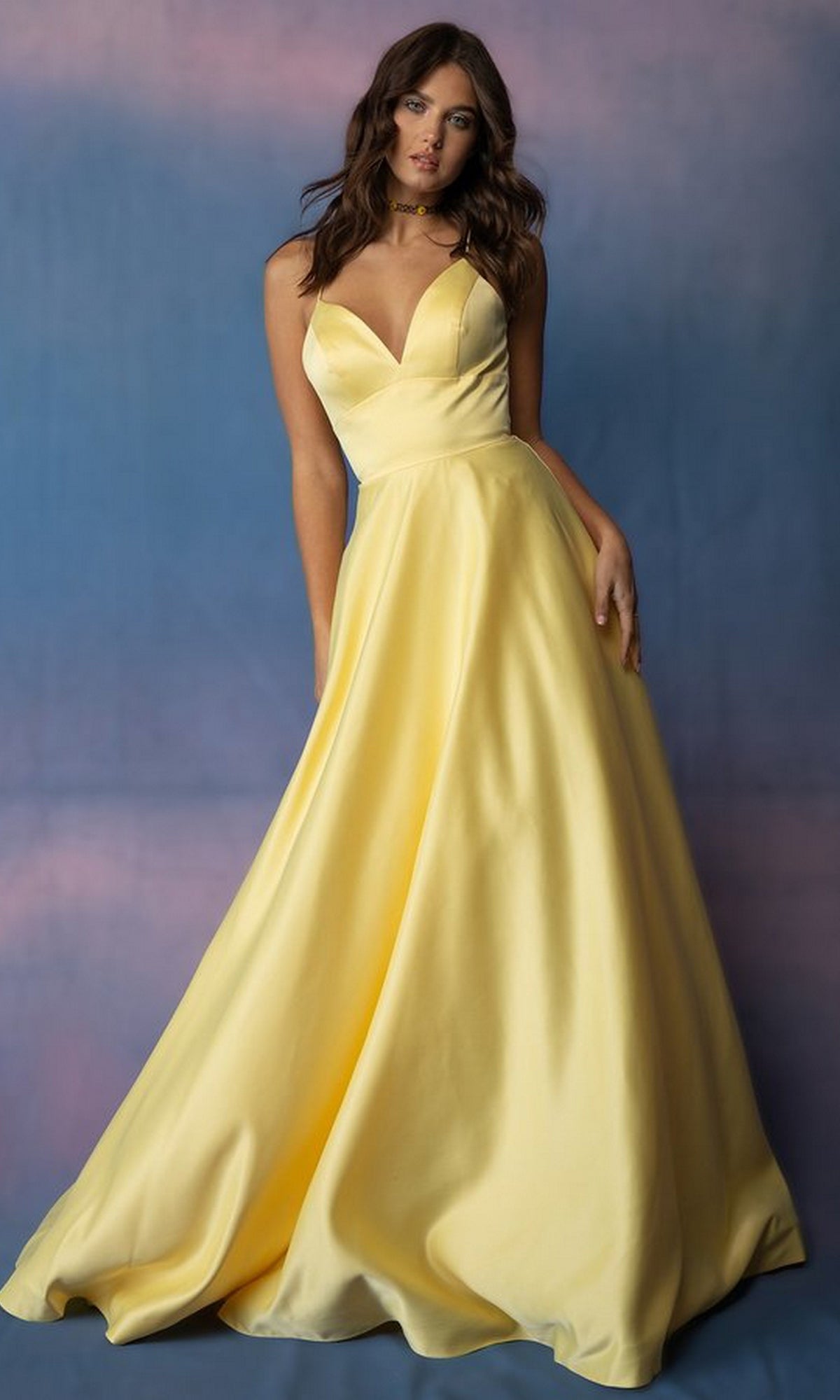 A woman wearing a yellow Eureka 9008 Strappy-Back Long Satin Prom Dress featuring a floor-length V-neck, spaghetti straps, and an open back.