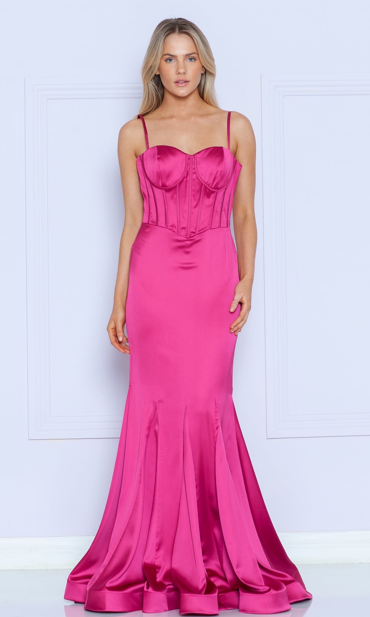 A woman poses against a light background in the Long Sweetheart Mermaid Corset Prom Dress 9008 in fuchsia, featuring thin straps, stretch charmeuse fabric, and a structured mermaid-style bodice.