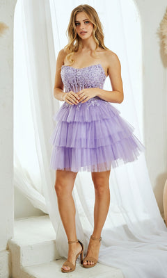 A woman stands indoors in the Strapless Ruffle Hoco Dress: Amelia Couture 9066S, a short strapless glitter dress with lilac tiered tulle, floral accents, and beige high-heeled sandals.