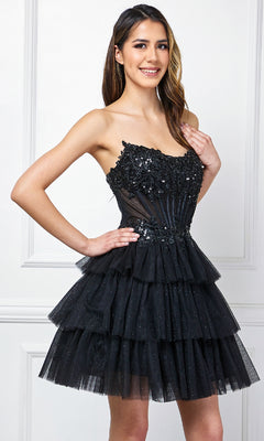 A woman smiles in front of a white wall, wearing the Amelia Couture 9066S Strapless Ruffle Hoco Dress featuring a short A-line design with tiered tulle and floral embellishments.