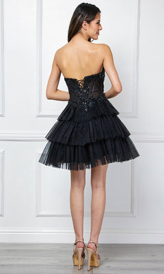Woman indoors wearing the Amelia Couture 9066S Strapless Ruffle Hoco Dress—a black, tiered tulle mini with lace-up back and high heels. This chic short A-line dress is perfect for parties and any special occasion.
