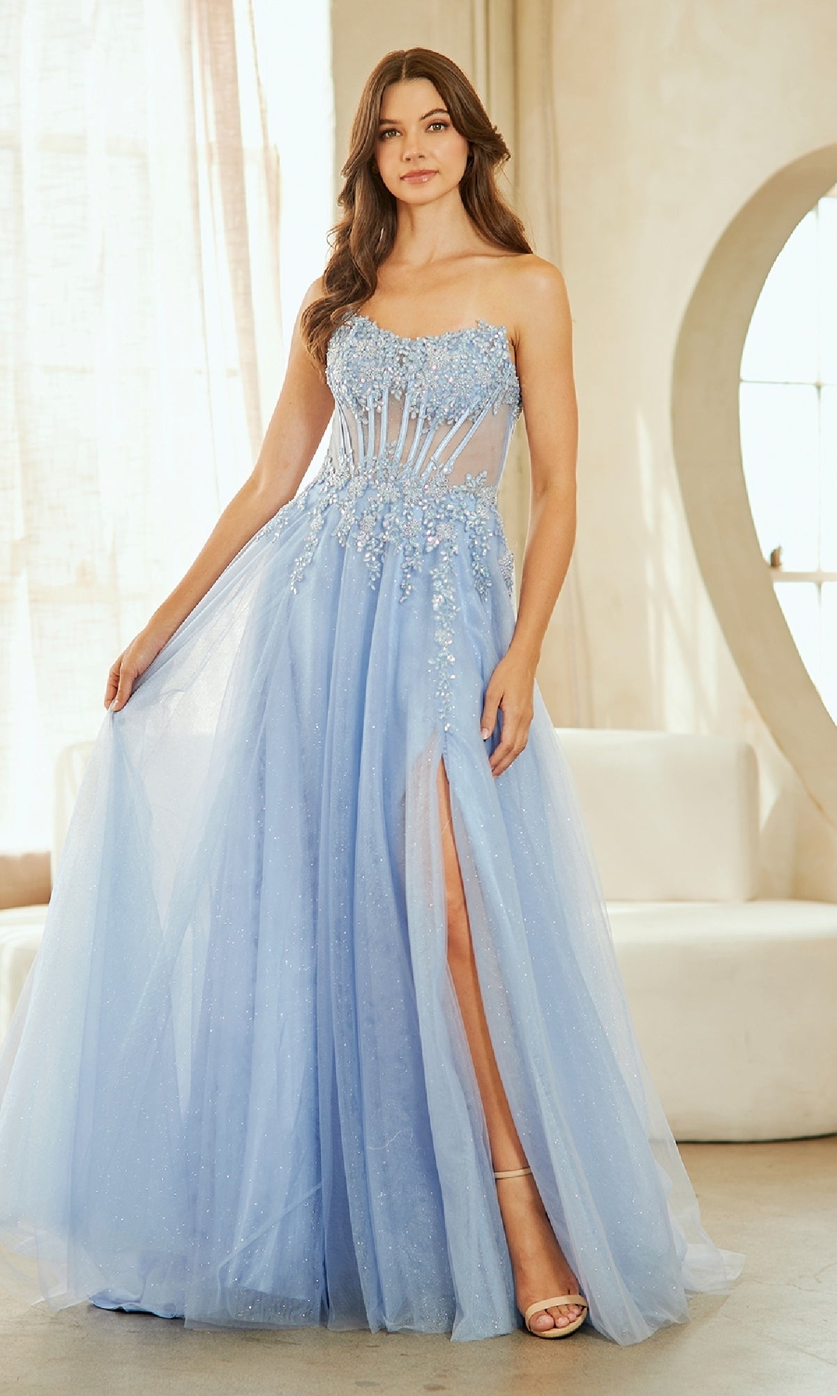 Woman wearing a light blue evening gown with a slit in a bright room.