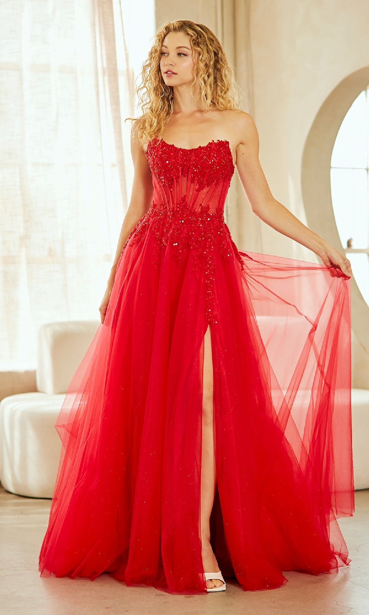 Woman wearing a red evening gown with a high slit in a well-lit room.