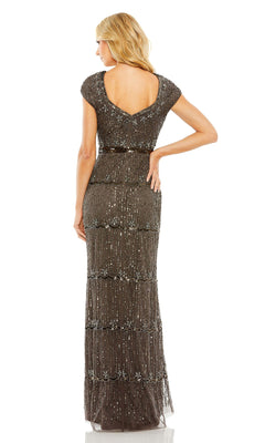 A woman stands with her back to the camera, wearing the floor-length Mac Duggal 9089 Cap-Sleeve Beaded Formal Dress, featuring cap sleeves, dark beading, and an elegant scoop back.