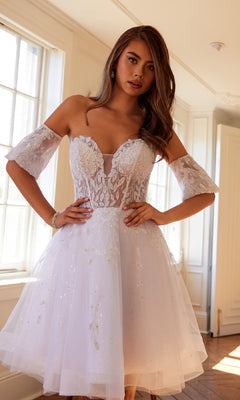 Woman wearing the Bell-Sleeve Short Sweetheart Prom Dress 909, a short white off-the-shoulder dress with lace and floral embroidery, featuring delicate floral details, standing indoors with hands on hips.