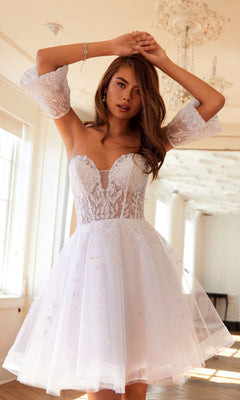 A woman poses gracefully in a bright, ornate room, wearing the Bell-Sleeve Short Sweetheart Prom Dress 909 with a corset bodice and delicate floral embroidery.