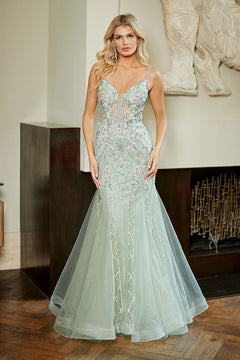 Amelia Couture 9104 mermaid prom dress in sage green with a V-neckline, sheer bodice, and silver beaded embellishments.