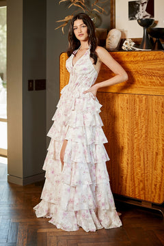 A woman wearing an Amelia Couture 9105 long floral prom dress with a halter V-neck, a corset bodice, and a tiered, ruffled skirt with a high front slit.